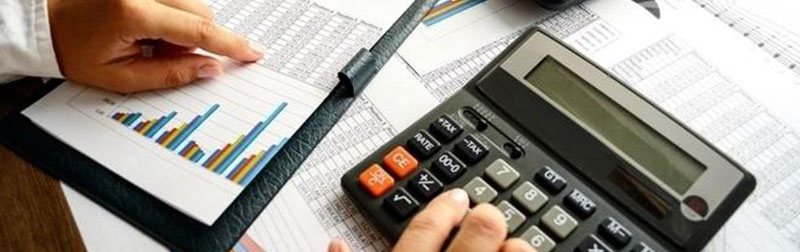 Business man using calculator and charts to create a realistic financial budget