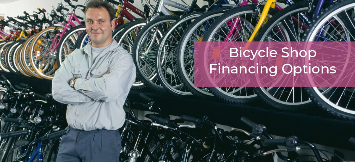 Man standing in front of a row of bicycles in his bicycle shop