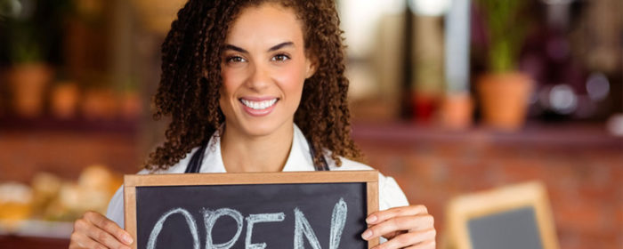 African American female business owner holding an open sign