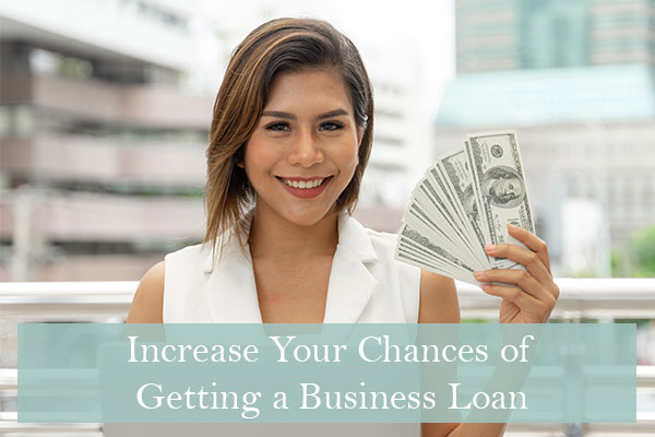 Woman holding up cash after improving her chance of getting a business loan